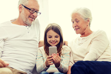 Image showing smiling family with smartphone at home