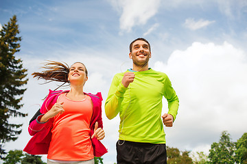 Image showing smiling couple with earphones running outdoors