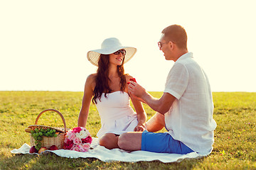 Image showing smiling couple with small red gift box on picnic