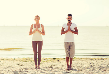 Image showing smiling couple making yoga exercises outdoors