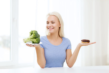 Image showing smiling woman with broccoli and donut at home