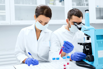 Image showing scientists with clipboard and microscope in lab