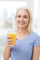 Image showing smiling woman drinking orange juice at home