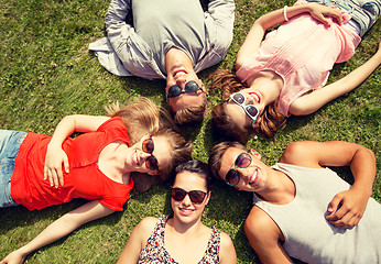 Image showing group of smiling friends lying on grass outdoors