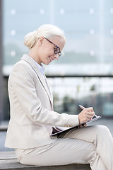 Image showing young smiling businesswoman with notepad outdoors