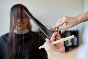 Image showing happy woman with stylist cutting hair at salon