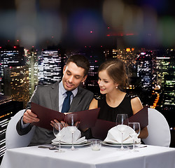 Image showing smiling couple with menus at restaurant