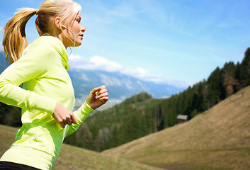 Image showing happy young woman with earphones jogging outdoors