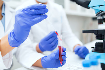 Image showing close up of scientists filling test tube in lab