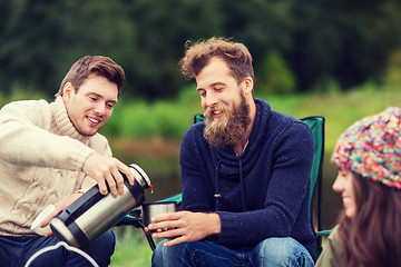 Image showing group of smiling tourists cooking food in camping