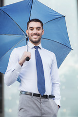 Image showing young smiling businessman with umbrella outdoors