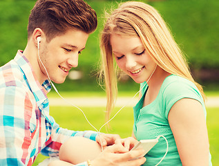 Image showing smiling couple with smartphone and earphones