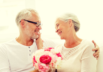 Image showing happy senior couple with bunch of flowers at home