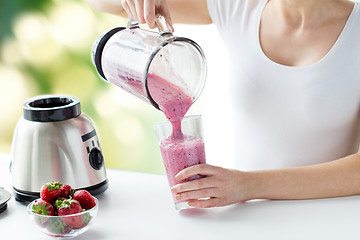 Image showing close up of woman with blender pouring milk shake