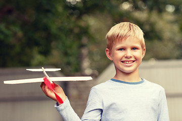 Image showing smiling little boy holding a wooden airplane model