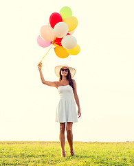 Image showing smiling young woman in sunglasses with balloons