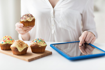 Image showing close up of woman with cupcakes and tablet pc
