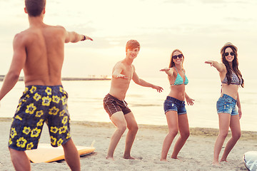 Image showing smiling friends in sunglasses with surfs on beach