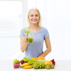 Image showing smiling woman drinking juice or shake at home