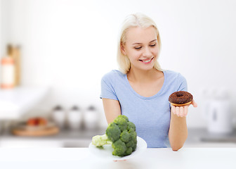 Image showing smiling woman with broccoli and donut on kitchen