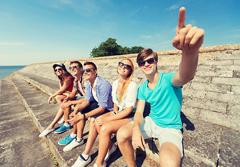 Image showing group of smiling friends sitting on city street