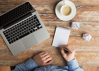 Image showing close up of male hands with laptop and notebook