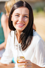 Image showing girl with drink and friends on the beach