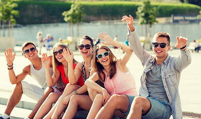 Image showing group of laughing friends sitting on city square