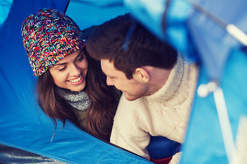 Image showing smiling couple of tourists looking out from tent