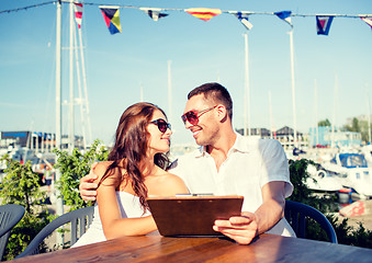 Image showing smiling couple with menu at cafe