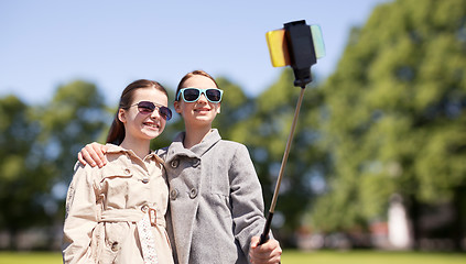 Image showing happy girls with smartphone selfie stick in park