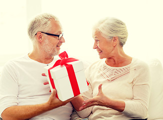 Image showing happy senior couple with gift box at home