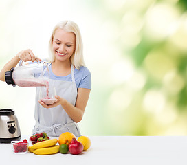 Image showing smiling woman with blender and fruit milk shake