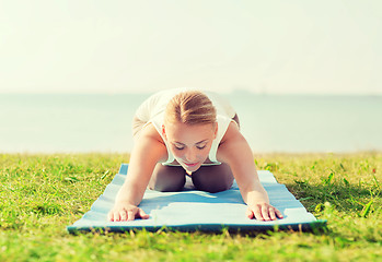 Image showing young woman making yoga exercises outdoors