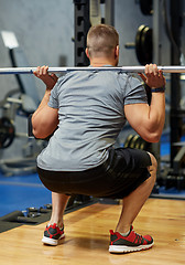 Image showing young man flexing muscles with barbell in gym