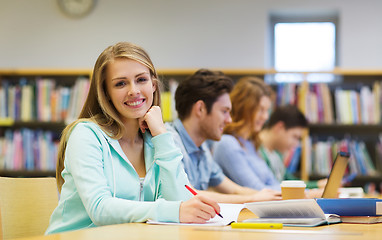 Image showing happy student girl writing to notebook in library