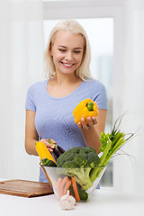 Image showing smiling young woman cooking vegetables at home