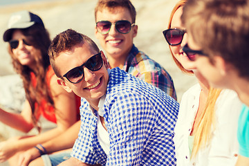 Image showing close up of smiling friends sitting on city street