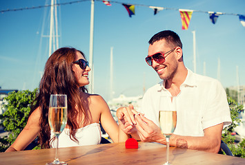 Image showing smiling couple with champagne and gift at cafe