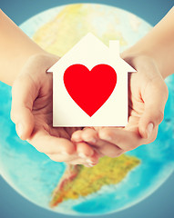 Image showing human hands holding paper house with red heart