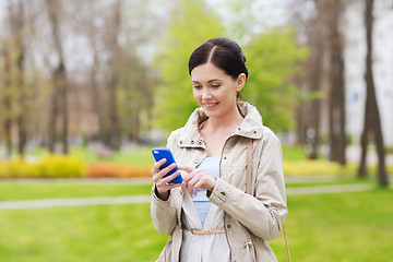 Image showing smiling woman calling on smartphone in park