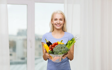 Image showing smiling young woman with vegetables at home
