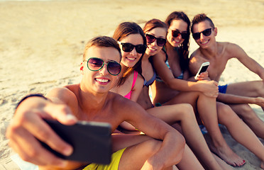 Image showing friends with smartphones on beach