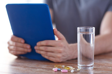 Image showing close up of hands with tablet pc, pills and water