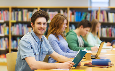 Image showing happy student boy reading books in library