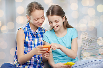 Image showing happy girls with smartphones sitting on sofa