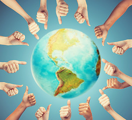 Image showing human hands showing thumbs up in circle over earth