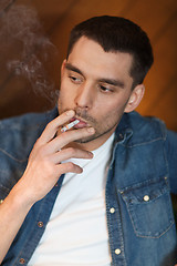 Image showing young man smoking cigarette at bar