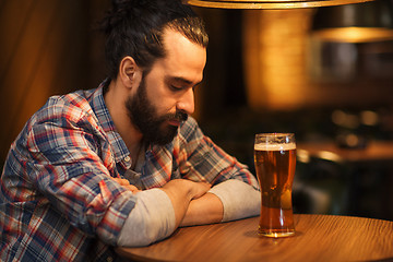 Image showing unhappy lonely man drinking beer at bar or pub