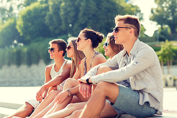 Image showing group of smiling friends sitting on city square